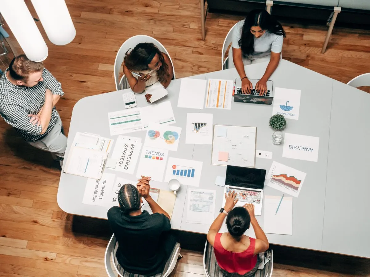 Profissionais analisando relatórios e planejando ações de marketing em uma mesa de trabalho, imagem ilustrativa